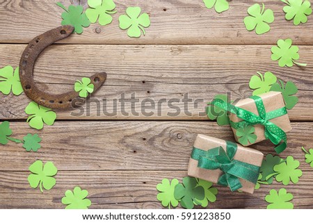 Background with rusty horseshoe, clover leaves and gift boxes on the old wooden boards. St.Patrick's day holiday symbol. Lucky charms. Space for text.