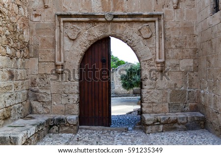Old wooden open door on a stone wall: a way out of the castle Royalty-Free Stock Photo #591235349