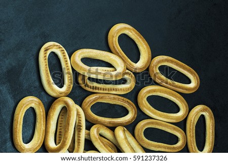 Many a bunch of bagels laid out on the dark surface of the table. Closeup, top view