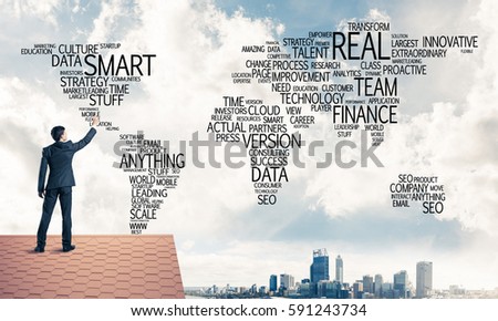 Young businessman standing on house roof and writing business related words. Mixed media