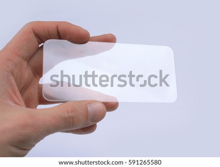 transparent glass phone in man's hand on a gray background
