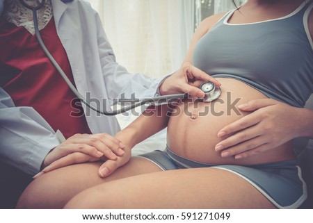 Cropped image of doctor using stethoscope examining pregnant woman Royalty-Free Stock Photo #591271049