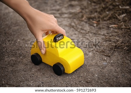 Woman holding yellow toy taxi on ground