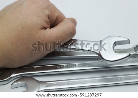Hand holding a ring spanners on a white background.