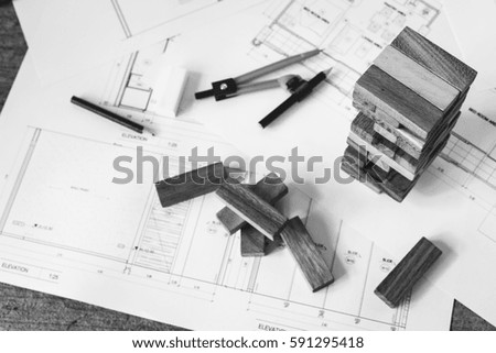 the blocks wood tower game with architectural plans, compasses ,pencils and ruler on wooden table,monochrome filter