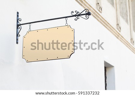 Horizontal front view of empty square vintage signage on a white building with classical architecture hanging with chains
