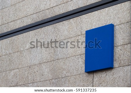 Horizontal side view of empty square blue signage on business building covered in marble