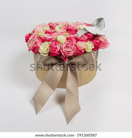 Brown silk ribbon holds round box with pink roses