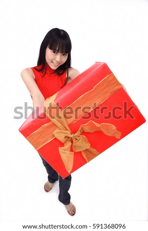 Young woman holding big red gift box towards camera