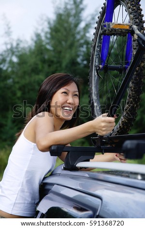 Woman securing bike on top of car