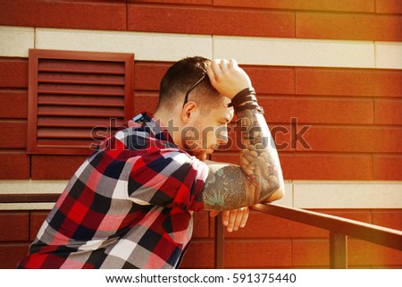 Young tattooed man posing on brick wall background