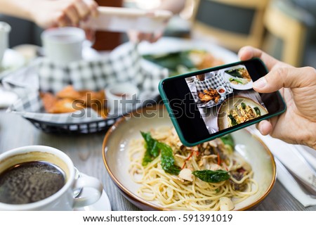 Friends taking photo on cellphone in restaurant