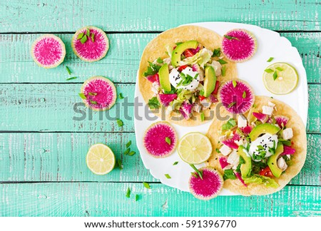 Healthy mexican corn tacos with boiled chicken breast, avocado and watermelon radish and yogurt dressing. Flat lay. Top view