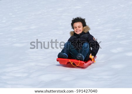 Happy young brothers on sled walking in winter outdoors
