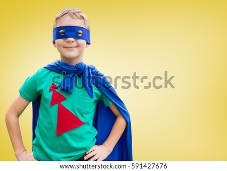 Boy in superhero costume standing with his hands on his waist against yellow background