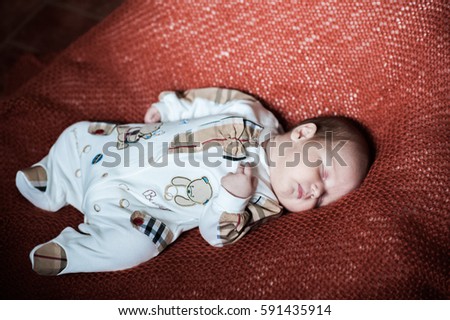 Beautiful baby lies. Firstborn is trying to keep his head on the weight. The blue-eyed baby boy asleep on a knitted blanket 