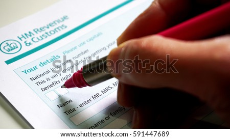 Photo of filling in a HM customs form a personal details for UK self assessment tax and benefits right. Royalty-Free Stock Photo #591447689