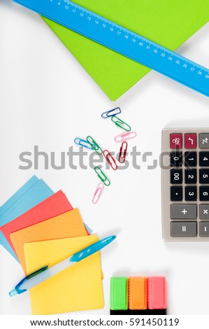office, school, business, education and technology concept - close up of notebook, paper stickers, pencil, clip, calculator, different stuff on white background
