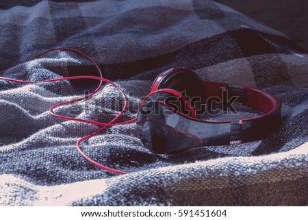 Photo of black and red headphones laying on the checked patterned blanket with red filter