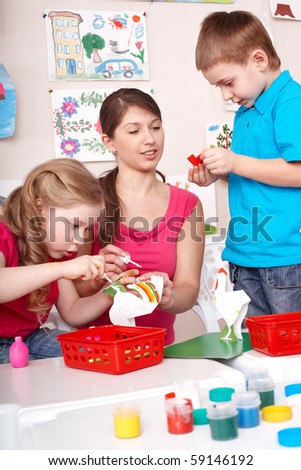 Children painting with teacher in play room.