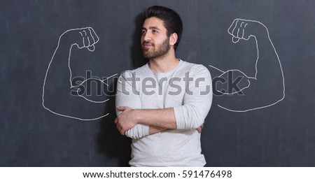 Young man against the background of depicted muscles on chalkboard