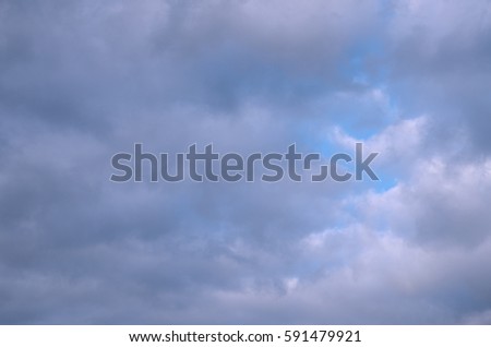 Cloudy sky of cold blue hue with a gap heaven. Abstract background of autumn clouds.