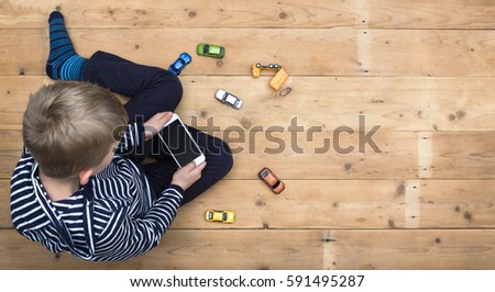 Young boy playing with smartphone instead of toys Royalty-Free Stock Photo #591495287