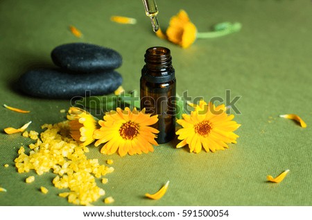Essential aroma oil with calendula on green background. Selective focus.