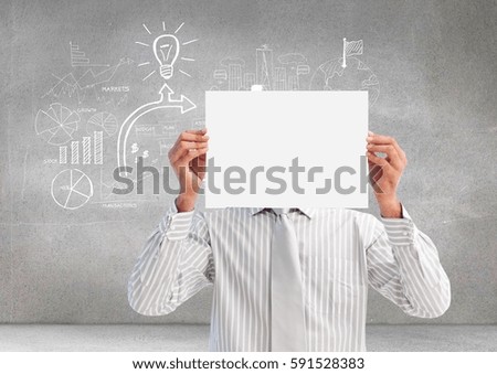 Businessman holding a blank placard in front of his face against grey background with graphics