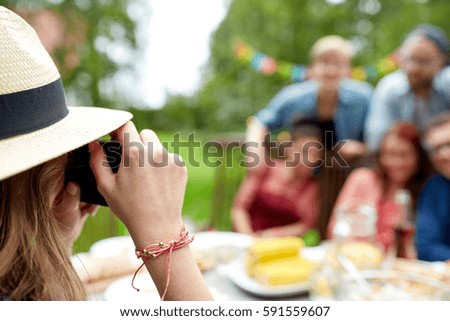 leisure, holidays and people concept - happy friends having dinner and photographing at summer garden party
