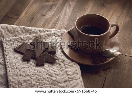 brown cup with black coffee saucer US, crushed chocolate, a spoon colored embroidered stitches gray linen towels, tablecloths on the old brown wooden background close plan