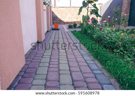 Nested pavers of various colors, around the grass is green, chic garden and the flowers bloom