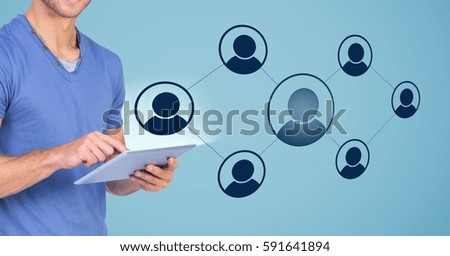 Man using digital tablet against digitally generated icons on blue background