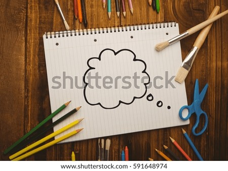 Thought bubble drawn on notebook placed with coloring tools against wooden background