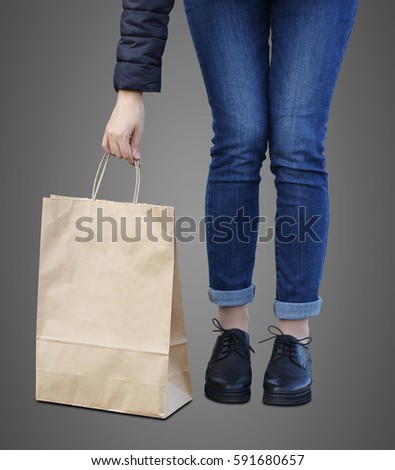 Girl holding ecological shopping with paper bag in hands. Isolated on grey background