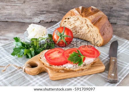 Easy vegetarian sandwich fresh tomatoes greens, cream cheese, crispy bread wooden table. A healthy way of life. Dark background horizontal frame