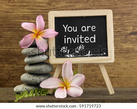 stack of pebbles and mini blackboard with text you are invited