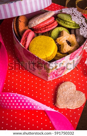 Box with macaroon and cookies on bright background