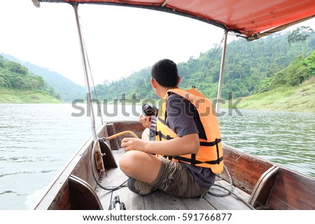man tourist with life jacket orange color enjoying on gondola . Traveling river and hold camera relaxing