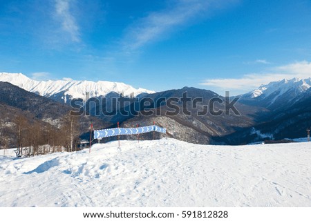 Blue sky and snowy peak of mountain view from the top of winter hill. Blue track for tourists with ski and snowboards.