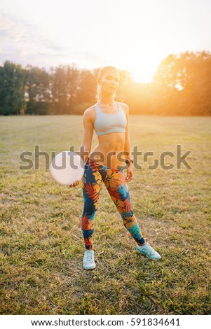 Young athletic girl playing with flying disc in the park. Professional player. Sport concept