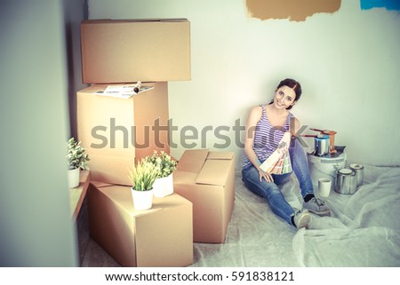 Woman choosing paint colour from swatch for new home sitting on wooden floor