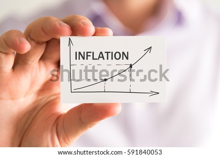 Closeup on businessman holding a card with INFLATION rising arrow and chart, business concept image with soft focus background Royalty-Free Stock Photo #591840053
