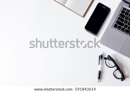 White office desk table with laptop, notebook, smartphone, and smartphone. Top view with copy space, flat lay.