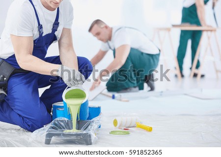 Professional interior construction worker pouring green color to paint Royalty-Free Stock Photo #591852365