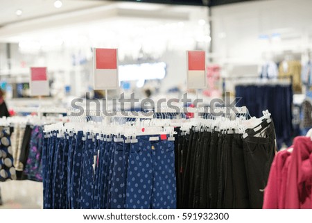 Variety of bright colour and patterns jeans on hangers in kids clothes store