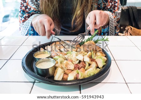 women cuts pork steak on the plate