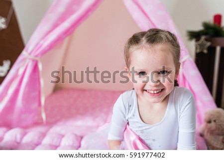 Little girl playing in a tent.