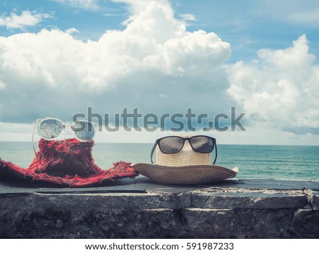 Hat and glasses on stone bench at the beach.