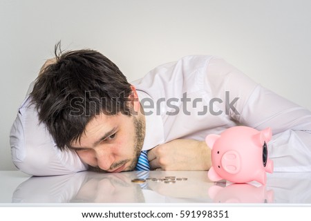 Young worried man has empty piggy money bank. Royalty-Free Stock Photo #591998351